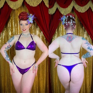 May include: Purple sequined lingerie set with a halter top and a low-rise bottom. The set is shown on a model with a tattoo on her back.