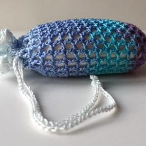 May include: A crocheted soap sack with a drawstring closure. The sack is made with a blue and purple ombre yarn and has a white drawstring.