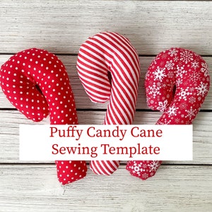 Puede incluir: Tres patrones de costura de bastones de caramelo hinchados rojos y blancos. Los bastones de caramelo están decorados con lunares, rayas y copos de nieve.