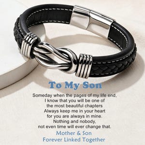 Puede incluir: Pulsera de cuero negro con diseño trenzado y cierre plateado en forma de nudo. El texto "To My Son" se muestra en azul, junto con un mensaje sentimental de "Mother & Son".