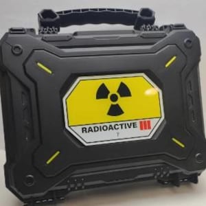 May include: Black hard-sided case with a yellow and black radioactive symbol sticker. The sticker says "RADIOACTIVE III".