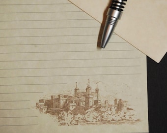 May include: A lined sheet of paper with a pen and a drawing of a castle on it. The castle is drawn in brown ink and is surrounded by trees and water.