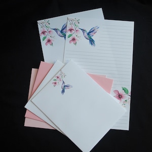 May include: Set of stationery featuring a hummingbird and pink flowers. The stationery includes envelopes and lined writing paper.