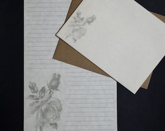 May include: A set of stationery featuring a white envelope and lined paper with a gray floral design. The paper has a subtle gray pattern and lined writing space.