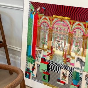 May include: A framed print of a colorful, surrealist artwork featuring a grand theater with a checkered floor, a tiger, a zebra, and various other animals and objects. The text "GRAND THEATRE NOUVEAU" is visible at the top of the image.