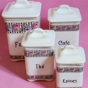 Puede incluir: Conjunto de cuatro botes de cerámica blanca con diseños a cuadros blanco y negro y florales. Los botes están etiquetados como "Farine", "Cafe", "The" y "Epices".