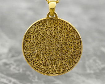 May include: A gold pendant necklace with a round charm featuring intricate Arabic calligraphy.