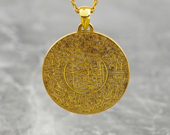 Può includere: Una collana con un ciondolo rotondo in oro decorato con calligrafia araba intricata. Il ciondolo è inciso con un design circolare e un'iscrizione centrale.