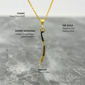 May include: A gold pendant necklace featuring a stylized sword design with black accents. The pendant is made of 18k gold plated on 925 sterling silver and weighs 0.99 grams or 0.34 ounces. The necklace is on a gold chain.