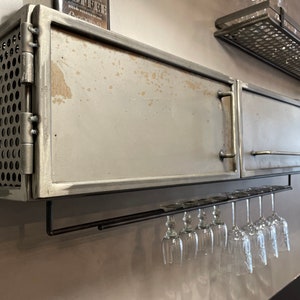 May include: A metal cabinet with a door and a mesh side panel. The cabinet has a metal wine glass rack underneath.