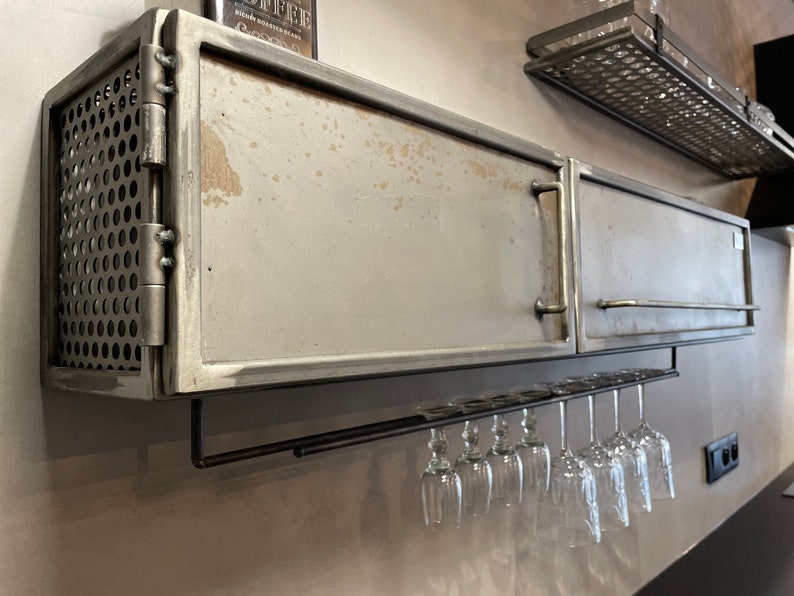 May include: A metal cabinet with a door and a mesh side panel. The cabinet has a metal wine glass rack underneath.