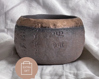 Handcrafted stoneware tea cup with embossed Heart Sutra design and gilded iron glaze, perfect for Zen enthusiasts.