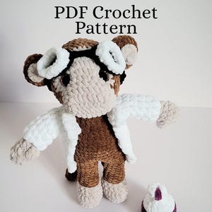 May include: A handmade crochet monkey doll with white goggles and a white lab coat. The monkey is brown and beige, with a small, detached purple and white accessory. The text "PDF Crochet Pattern" is at the top.