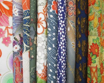 May include: A collection of colorful fabric rolls with floral and geometric patterns. The fabrics feature a variety of colors, including orange, pink, blue, green, and gold. The patterns include flowers, leaves, and abstract designs.