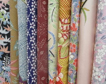 May include: A collection of vertical fabric strips featuring diverse patterns including floral motifs, geometric grids, and botanical designs in a palette of black, gold, blue, deep red, cream, yellow, green, and soft pink hues.