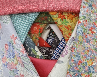 May include: A folded fabric craft project featuring a spiral arrangement of triangular fabric pieces. The design showcases a variety of patterns including floral, geometric, and leaf motifs in colors of red, blue, green, white, and gold.