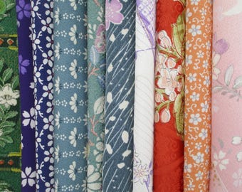 May include: A collection of vertical fabric strips featuring diverse patterns including floral motifs, cherry blossoms, and geometric designs in a vibrant color palette of green, purple, blue, teal, white, red, orange, and light pink.
