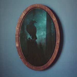 May include: A framed oval print of a raven perched on a branch in a foggy forest. The raven is black and the forest is a dark green.