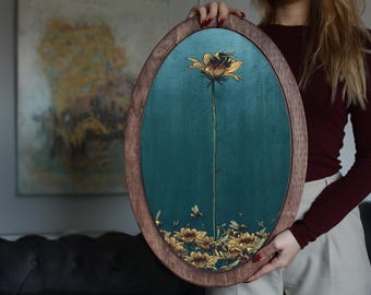May include: A wooden oval frame with a teal blue background and a gold painted flower with a bee on it. The flower is surrounded by smaller gold flowers.