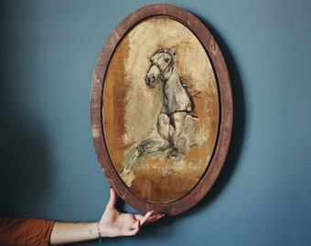 May include: A framed painting of a white horse with a brown bridle, set against a light brown background. The frame is oval and made of dark wood.