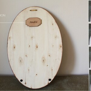 May include: A light wood oval-shaped sign with a small rectangular sign attached to it. The small sign says "Andre" in a cursive font. The text "FREE PERSONALIZATION" is written above the sign.