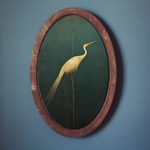 May include: A white bird with a long, thin neck and long, thin legs stands on a branch in a dark green oval frame. The bird is facing to the right and has a long, thin beak. The frame is made of wood and has a dark brown finish.
