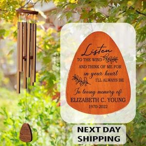 May include: A memorial wind chime with a wooden top and bronze-colored chimes. A wooden plaque with the text "Listen to the wind" and "In loving memory of Elizabeth C. Young 1970-2022" is also visible.