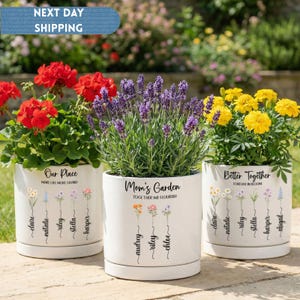 May include: Three white ceramic flower pots with colorful flowers. Each pot has a different inscription: "Our Place", "Mom's Garden", and "Better Together". The pots are decorated with floral illustrations and names.