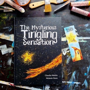 Könnte beinhalten: Das Cover des Buches "The Mysterious Tingling Sensations" zeigt einen schwarzen Hintergrund mit goldenem Glitzer und einen gelben und orangenen Kometen-Schweif. Der Buchtitel ist in Weiß mit schwarzem Umriss. Die Autoren sind Claudia Mathis und Melanie Gunz.