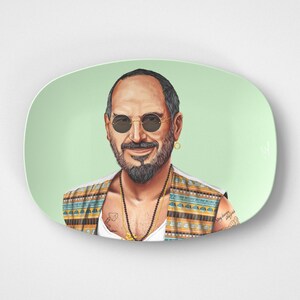 May include: A ceramic plate with a green background features a portrait of a man with a beard and sunglasses. He is wearing a colorful patterned vest and a gold necklace.