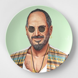 May include: A ceramic plate with a colorful illustration of a man wearing sunglasses, a patterned shirt, and a gold necklace. The background is a light green color.