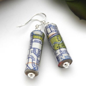 May include: A pair of silver earrings with map-themed pendants. The pendants are cylindrical and feature a vintage map design with blue and yellow accents. The text on the map includes "Center Park", "Boulder", "Tejon", "Cedar", "Buena Ventura", and "James Foote Ave."