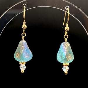 May include: A pair of gold dangle earrings with a teardrop-shaped blue glass bead and a clear crystal accent.