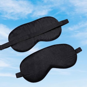 May include: Two black sleep masks with adjustable straps. The masks are made of a soft, comfortable material and are designed to block out light.