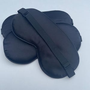 May include: Three black satin sleep masks with adjustable straps. The masks are designed to block out light and promote sleep.