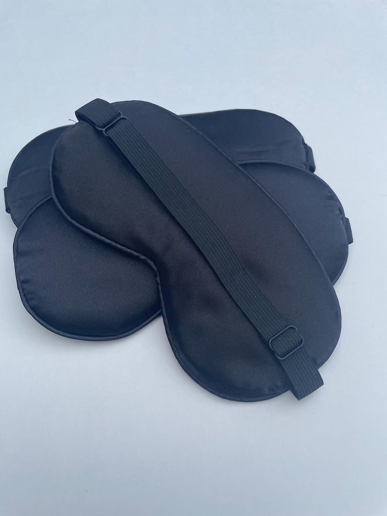 May include: Three black satin sleep masks with adjustable straps. The masks are designed to block out light and promote sleep.