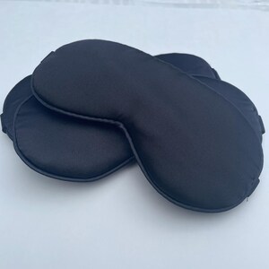 May include: Two black sleep masks made of soft, silky fabric. The masks are designed to block out light and help you sleep.