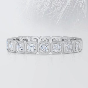 May include: A silver band with a row of square-shaped diamonds set in a bezel setting.