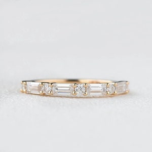 May include: A delicate gold band with a row of alternating round and baguette-shaped diamonds.