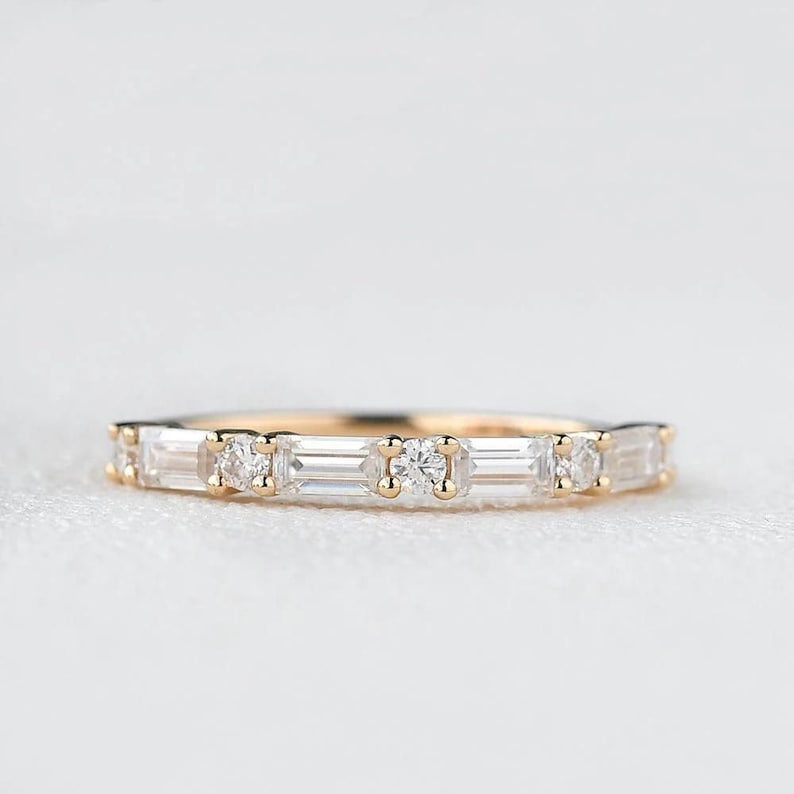 May include: A delicate gold band with a row of alternating round and baguette-shaped diamonds.