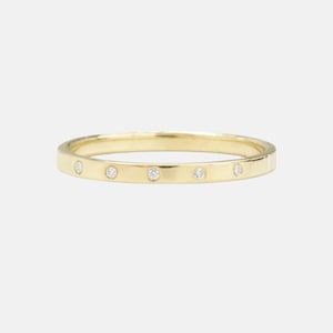 May include: A thin gold band ring with five small diamonds set into the band.