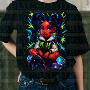 May include: Black t-shirt featuring a colorful illustration of a cartoon character with red skin, dark blue hair, and vampire fangs. The character is sitting on a coffin-shaped object. The design includes green and blue starbursts.