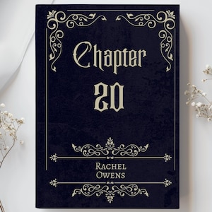 May include: A dark blue book cover with the title "Chapter 20" in an elegant font, framed by ornate scrollwork. The author's name, Rachel Owens, is also displayed. White flowers and fabric are in the background.