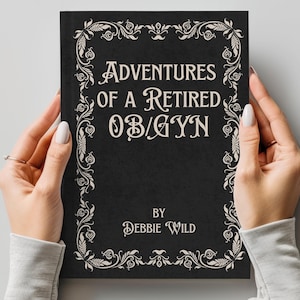 May include: A black book with a white ornate border and the title "Adventures of a Retired OB/GYN" by Debbie Wild.