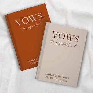 May include: Two hardcover vow books with matte finishes. The rust-colored book features white text reading VOWS to my wife, ASHLEY & OCTOBER. The beige book features dark brown text reading VOWS to my husband, ASHLEY & MATTHEW, OCTOBER 30, 2027.
