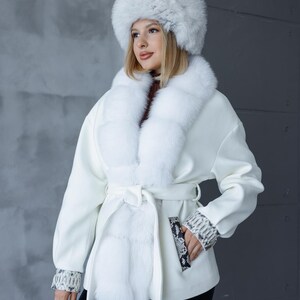 Peut inclure: Ensemble composé d'un chapeau et d'un manteau en fausse fourrure blancs. Le manteau présente un col en fourrure, une taille ceinturée et des poignets imprimés serpent. Un sac à main assorti complète le look. Un choix élégant pour l'hiver.