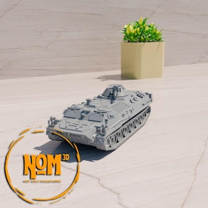 Può includere: Un modello in plastica grigia di un trasporto truppe corazzato militare con una torretta girevole. Il modello è su una superficie grigio chiaro.