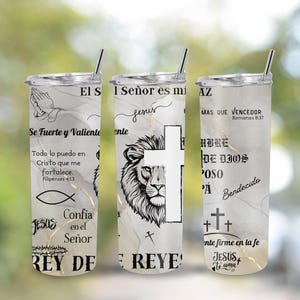 Puede incluir: Un juego de tres vasos de acero inoxidable con tapas y pajitas. Los vasos presentan un fondo similar al mármol con detalles dorados y texto e imágenes religiosas, incluyendo un león, una cruz y la palabra "Jesús".