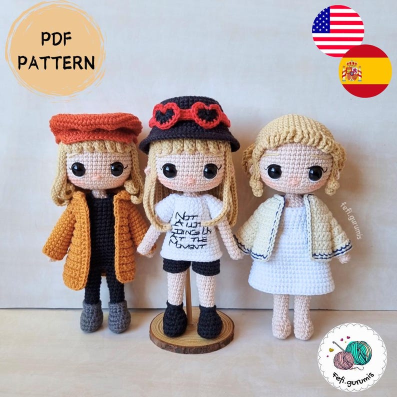 Op de afbeelding: Drie gehaakte poppen met blond haar en grote ogen. De poppen dragen verschillende outfits, waaronder een jas, hoed en korte broek. Op het shirt van &eacute;&eacute;n pop staat "Not all those who wander are lost". De afbeelding bevat de tekst "PDF PATTERN".