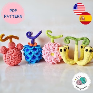 Puede incluir: Cuatro diseños de frutas de ganchillo coloridas. Las frutas son en tonos de rosa, azul y amarillo, con tallos verdes y morados. El texto "PDF PATTERN" está en un círculo rosa. La imagen también incluye las banderas estadounidense y española.